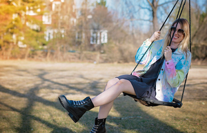 Adult tie dye boyfriend jacket modeled by girl on swing